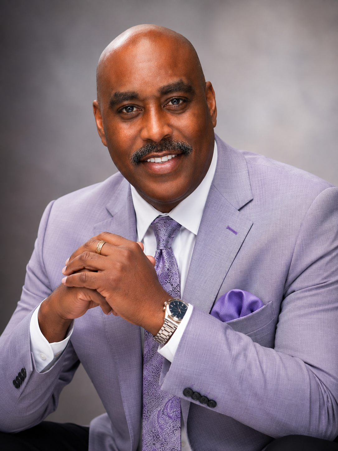 Dr. Melvin Futrell in a lavender suit with purple tie and pocket square